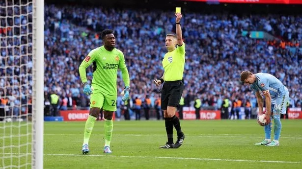 LONDON, ENGLAND - APRIL 21: Referee Robert Jones shows a yellow card to Andre Onana of Manchester United in the penalty shoot out during the Emirates FA Cup Semi Final match between Coventry City and Manchester United at Wembley Stadium on April 21, 2024 in London, England. (Photo by Richard Heathcote/Getty Images)